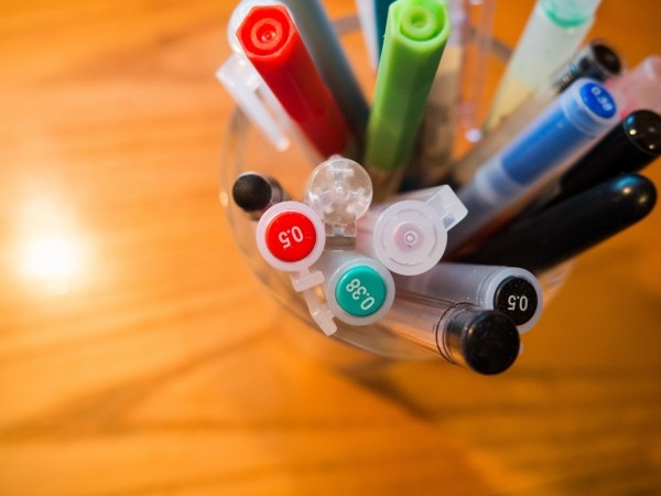 a cup of pens on a wooden table, shot from above.