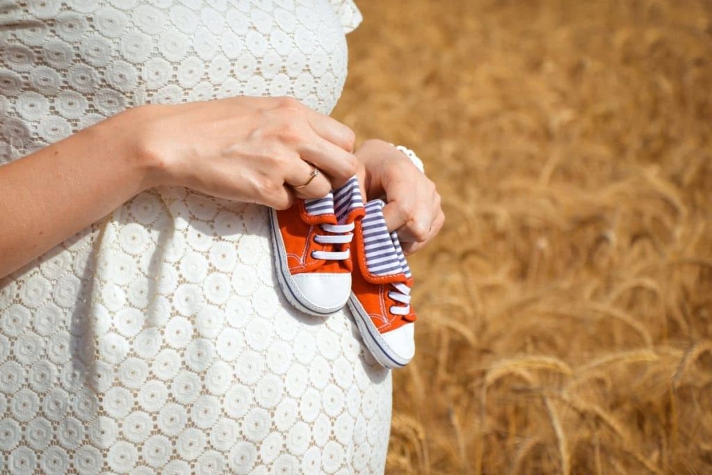 woman pregnant with baby, baby shoes