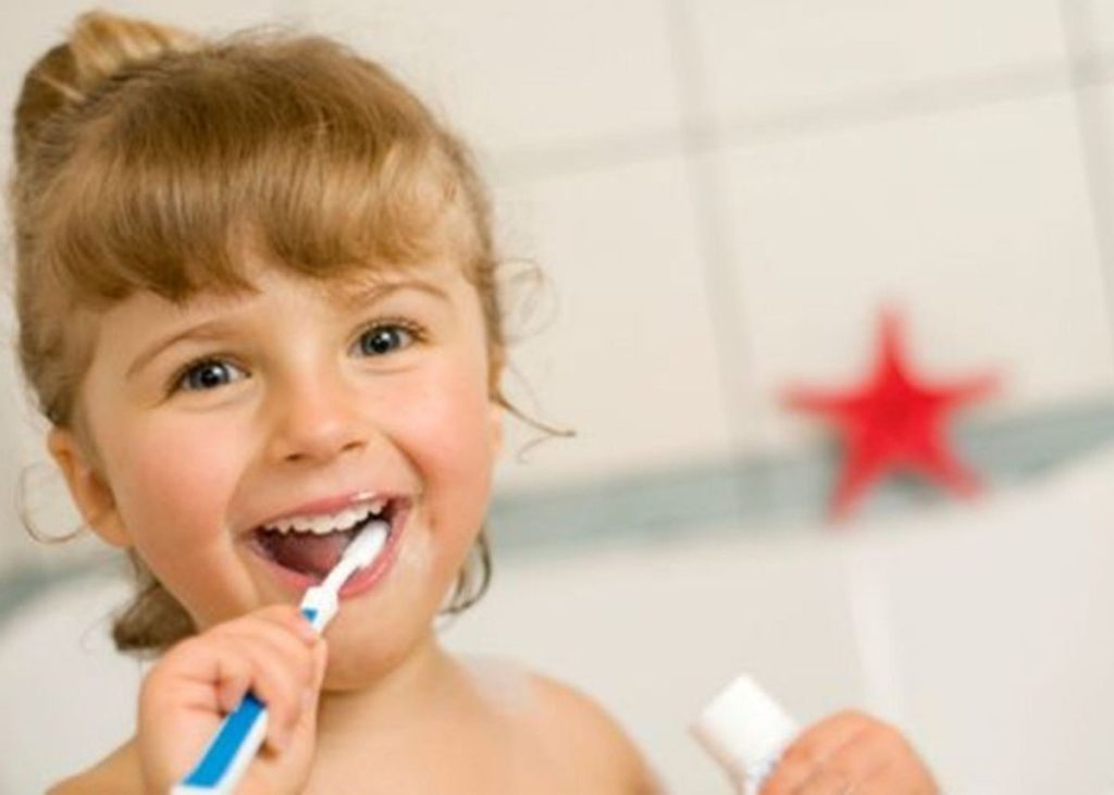 A toddler girl is brushing her teeth.