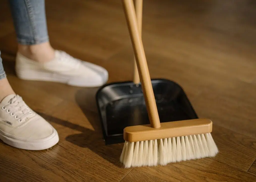 A mom sweeping the floor to keep their household clean.