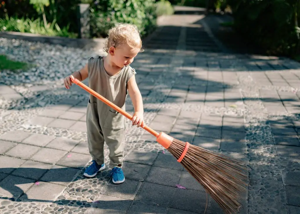 Toddler sweeping the patio teaching- toddler to help clean.