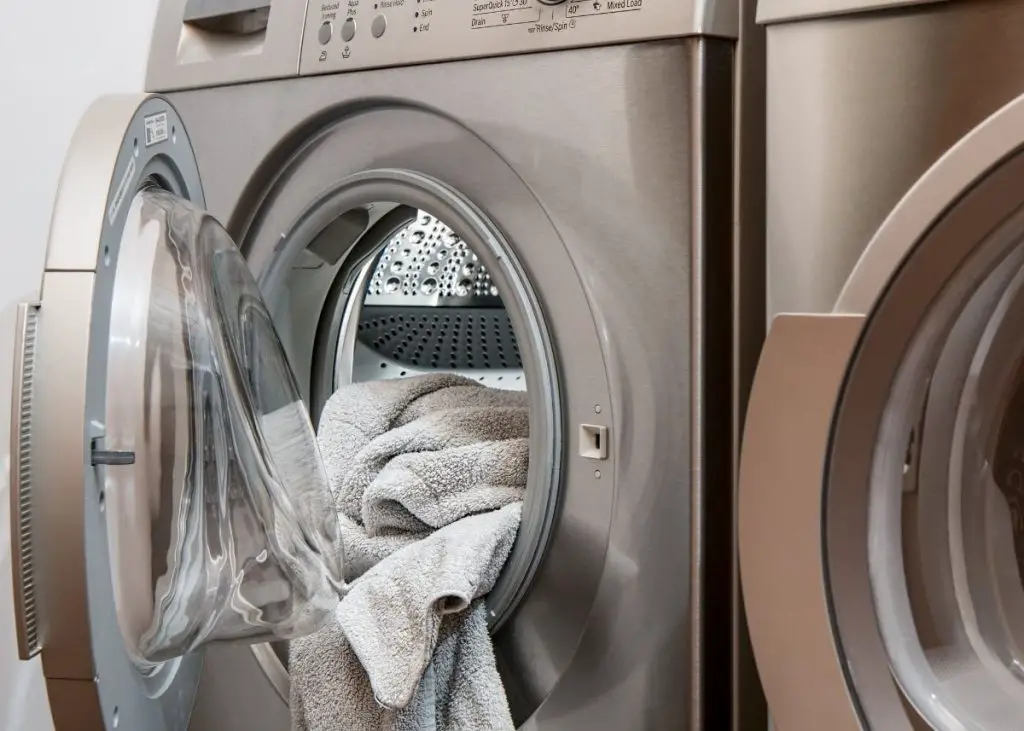 Towels being put into the washing machine as part of the household chores.
