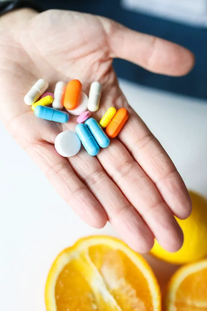 Someone is holding six different kinds of multicolored medicine in their hand.