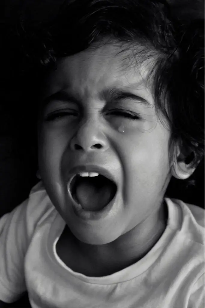 A toddler boy is crying.  The photo is in black and white.